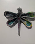 Handcrafted resin Dragonfly Wall Decor. Bring a touch of whimsy and color to your walls with this one-of-a-kind handmade resin dragonfly. Each wing is swirled with smoky gray, teal, golden yellow, and hints of magenta, giving it the look of stained glass catching the light. The glossy resin finish makes the colors pop and adds a beautiful depth when mounted against a wall. Because this piece is fully handmade and poured, it has a tiny intentional imperfection that makes it uniquely yours. It's part charm an