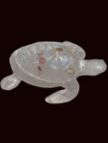 A translucent clear resin sea turtle figurine with small natural sea shells.