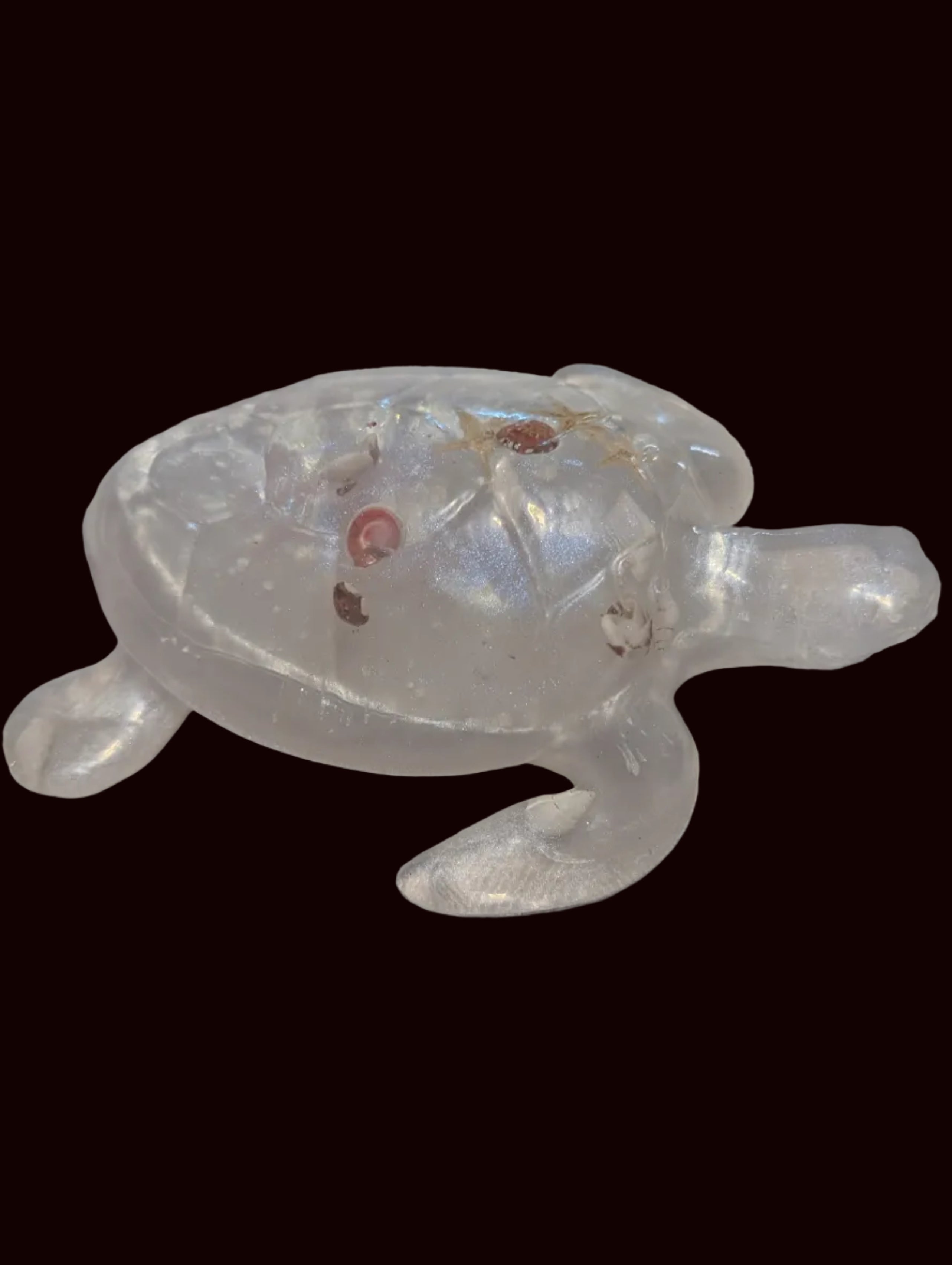 A translucent clear resin sea turtle figurine with small natural sea shells.