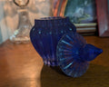 Handcrafted resin vase in a deep, starry blue with a frosted, beveled edge and subtle sparkle throughout. It has a rounded, ribbed body and a matching lid with a rounded finial, giving it an elegant, almost celestial feel. Perfect for adding a touch of handmade charm to any shelf or table. 